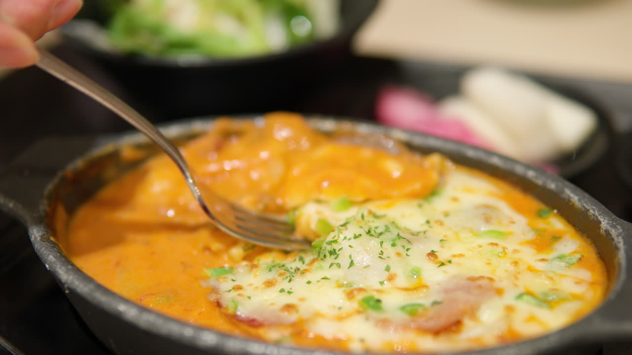 Female's hand picks up rose cheese potato gratin with fork - close-up slow motion