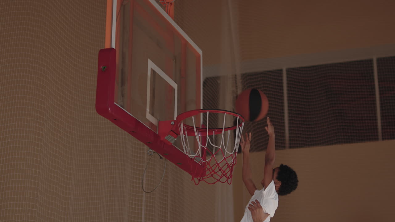 Father Helping Son Shoot Basketball on Indoor Court