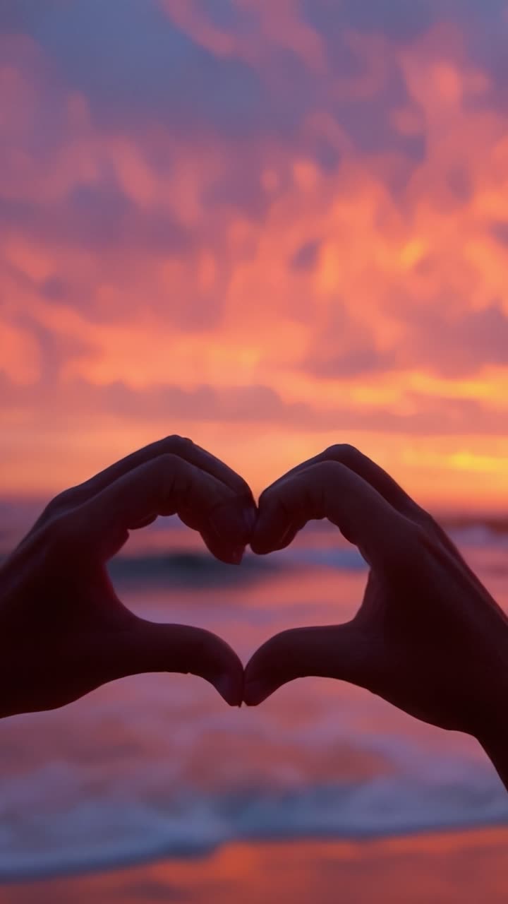 Um gesto sincero contra um pôr do sol deslumbrante, simbolizando amor e conexão num belo cenário costeiro.