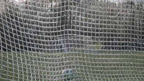 slow motion: a soccer ball slams, close up, into an icy net of a soccer goal exploding shattered ice into the air