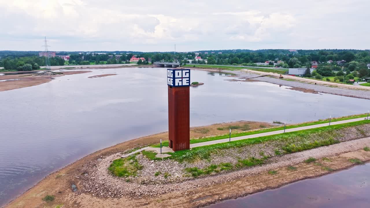 Aerial orbit around rusty river beacon in Ogre with moody water reflections