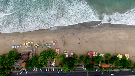 Sombrillas-De-Colores-En-La-Playa-De-Arena-De-Kuta-En-La-Isla-De-Bali,-Vista-Aérea-De-Arriba-Hacia-Abajo