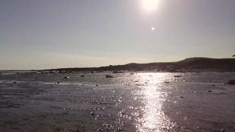 Vuelo-Bajo-Sobre-El-Río-Que-Se-Encuentra-Con-El-Mar-Bajo-El-Sol-Durante-El-Verano-Soleado-En-La-Península-De-Snaefellsness,-Islandia