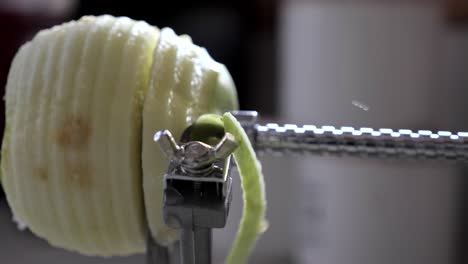 slow motion metal kitchen device peeling, cutting and core green juicy apple skin and flesh on kitchen bench