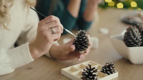 detail of unrecognizable woman and daughter decorating cone with white paint.