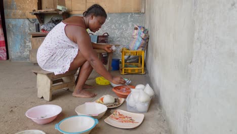 una mujer africana pone estofado y pescado en un plato para acompañar a banku, un dumpling típico de ghana