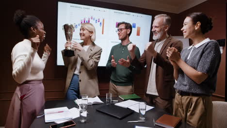 business team celebrating success with a trophy in a meeting room