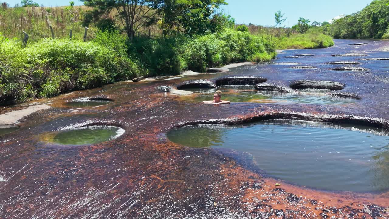 Aerial view of a woman bathing in the natural swimming pools of a river in colombia