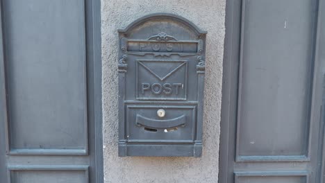 un buzón negro con una puerta de metal en una pared