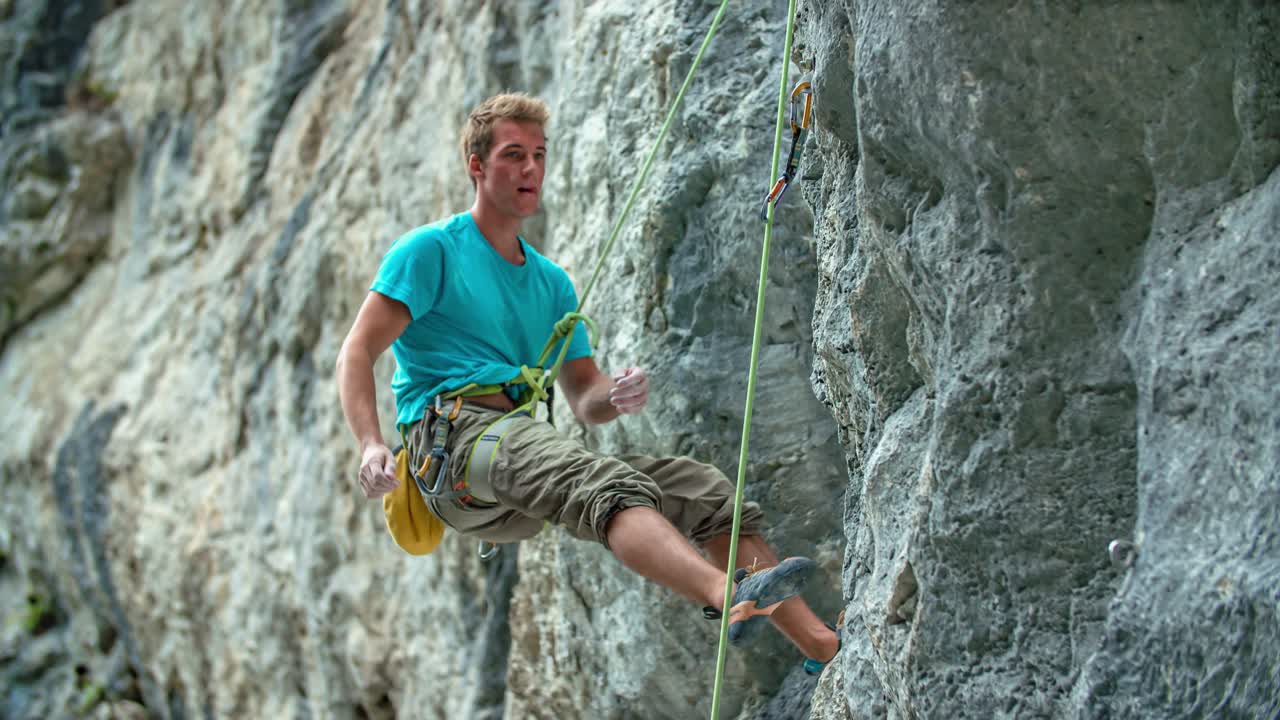 Rock climber athlete man climb down from cliff with a rope. Extreme sport