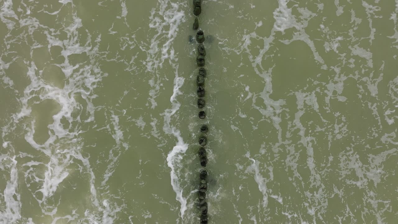 흐린 날, 오래된 목조 부두, 하얀 모래 해변, 해안을 짓누르는 큰 폭풍우, 기후 변화, 넓은 오름차순 드론 샷