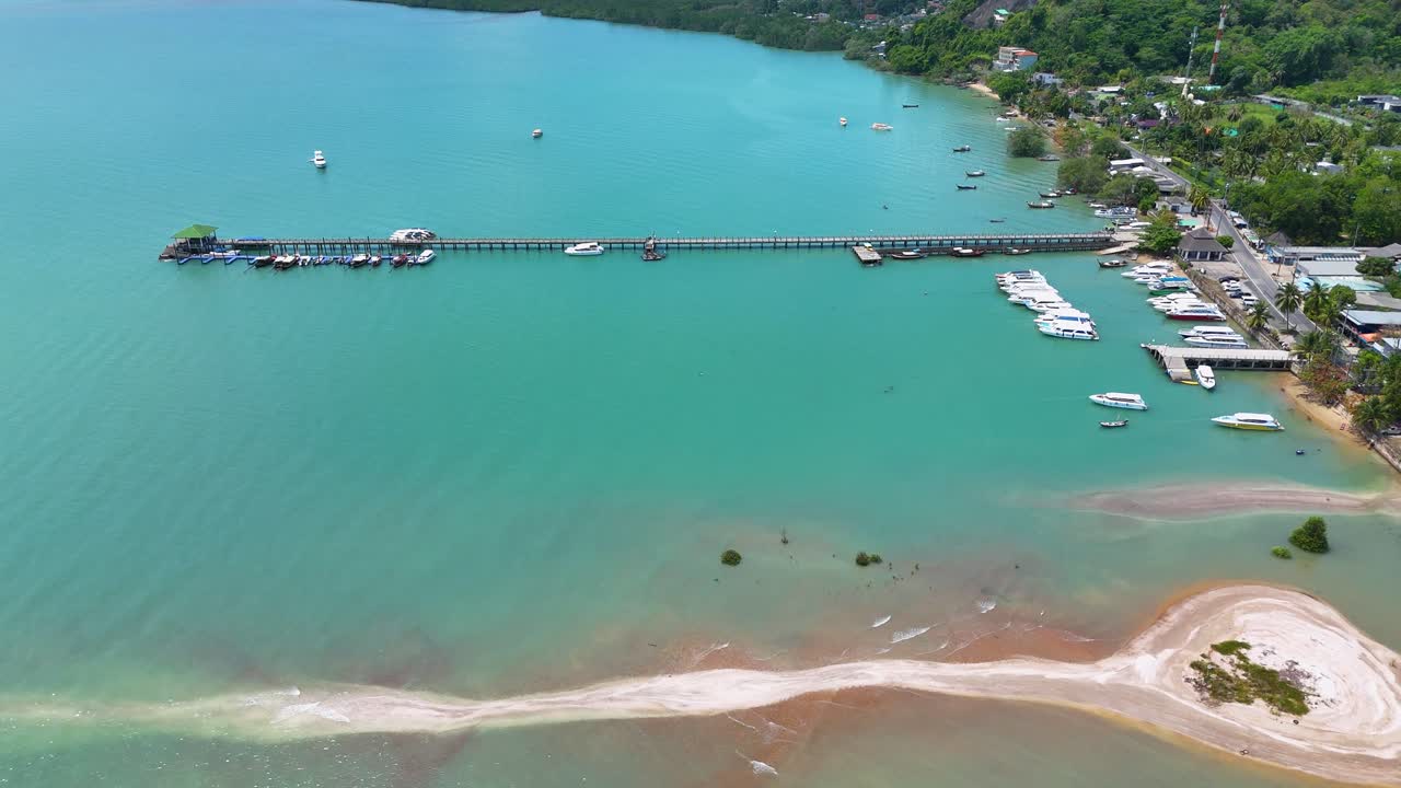 las imágenes aéreas capturan la vibrante costa de phuket, mostrando aguas turquesas, playas de arena y un bullicioso muelle con barcos