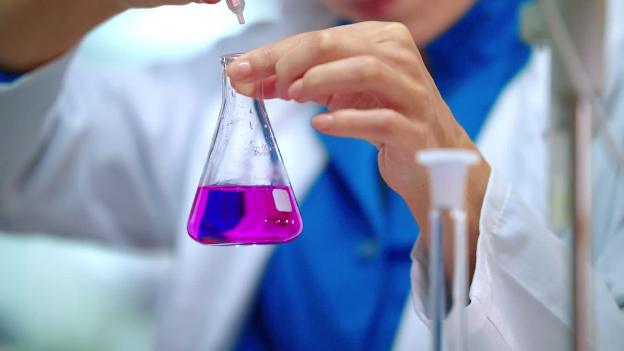 trabajador de laboratorio médico goteando reactivo en líquido químico en el frasco de laboratorio