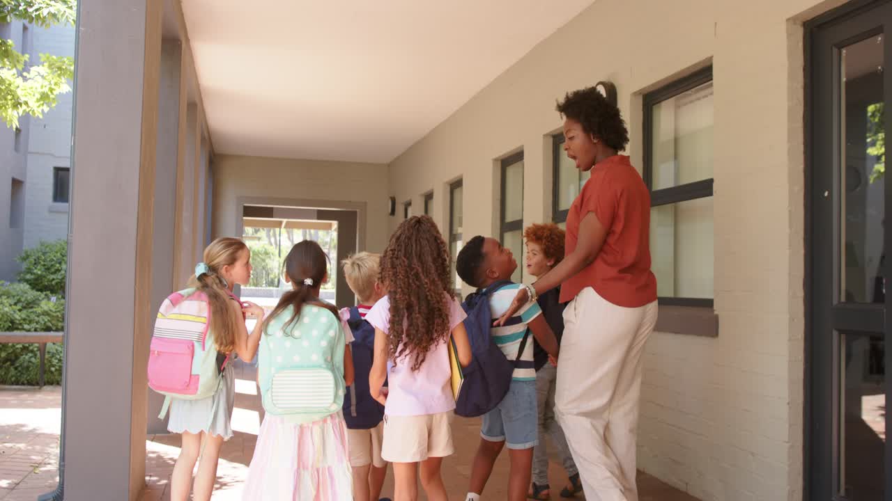 On kids arrival teacher in rust top greeting, guiding school children at door, adjusting backpacks