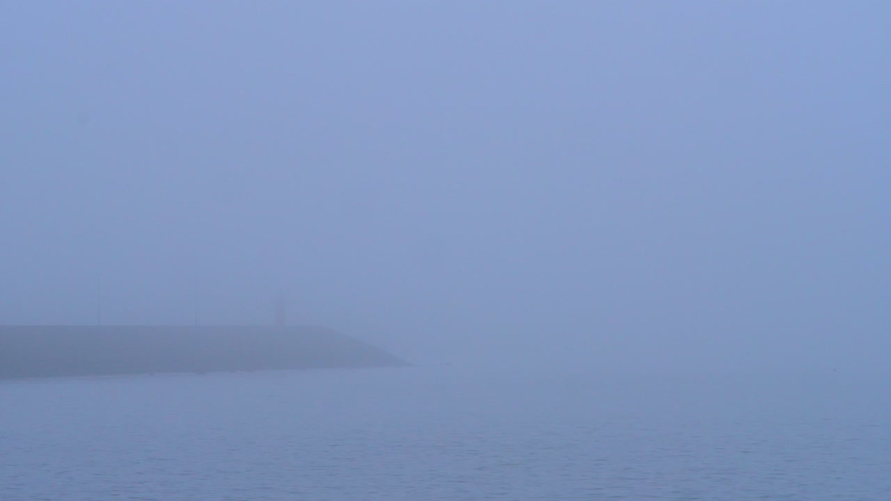 잔잔한 물과 형형색색의 하늘이 있는 일출 시 바다와 해변 마을의 안개