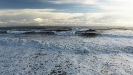 Vista-Aérea-Sobre-Grandes-Olas-En-La-Costa-Del-Sur-De-Islandia,-En-Parte,-Día-Soleado