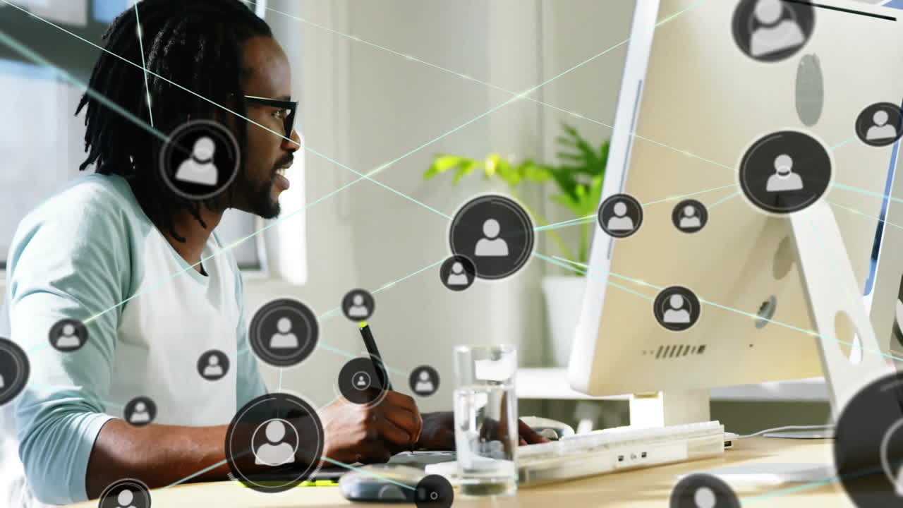 Animation of network of connections with icons over biracial businessman using computer