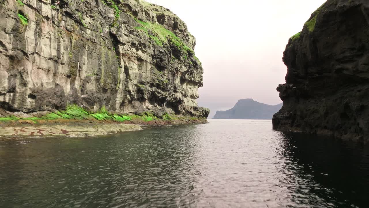 A serene fjord scene with towering cliffs in the Faroe Islands during calm weather