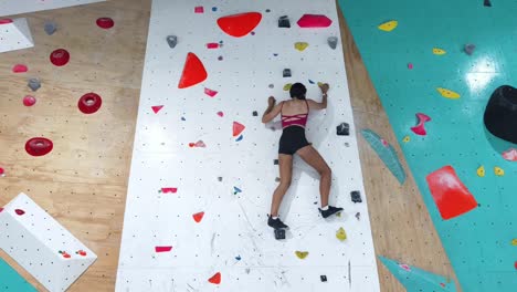 mujer bouldering en el gimnasio de escalada cubierto