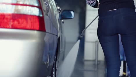 chica lava el coche con una pistola de pulverización