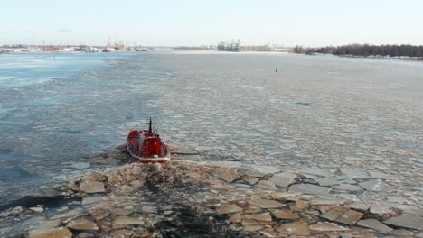 la vista aérea sigue a un pequeño barco rojo navegando a lo largo de témpanos de hielo a la deriva creando pequeñas olas onduladas