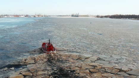 aerial view follows small red ship sailing along drifting ice floes creating small ripple waves