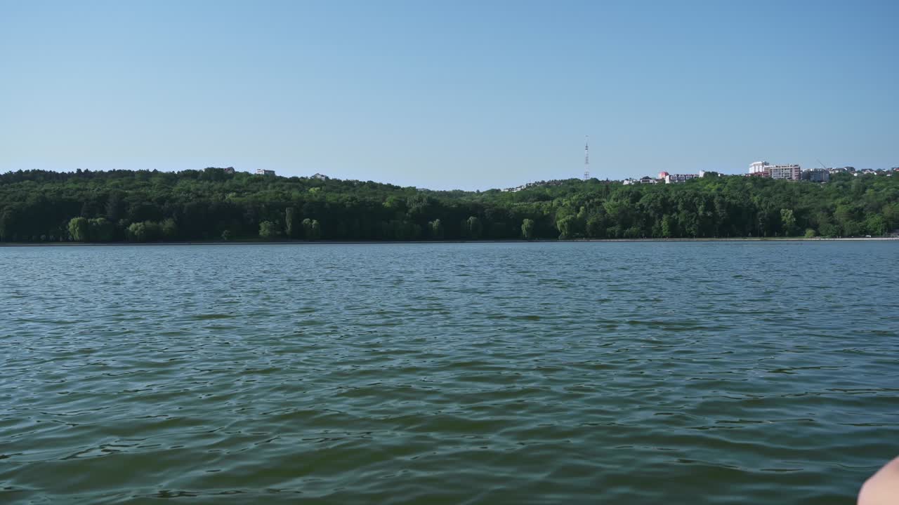 Young curly woman meditating while wearing black protective mask. Park and lake in background. Sunny day. Corona Virus idea. Chisinau, Moldova