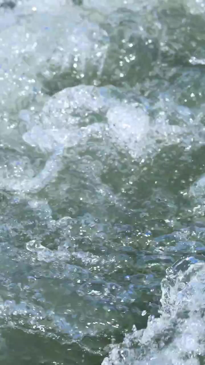 Primo piano del movimento turbolento dell'acqua nel torrente Glenorchy, che mostra motivi e texture naturali in piena luce diurna.