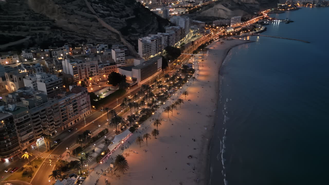 Aerial drone view of cars moving along the coastline in Alicante, Spain in the evening