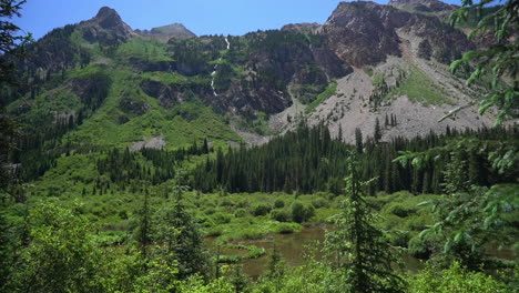 heavenly landscape of rocky mountains of sunny summer day, green valley and pond under hills, tilt down, full frame