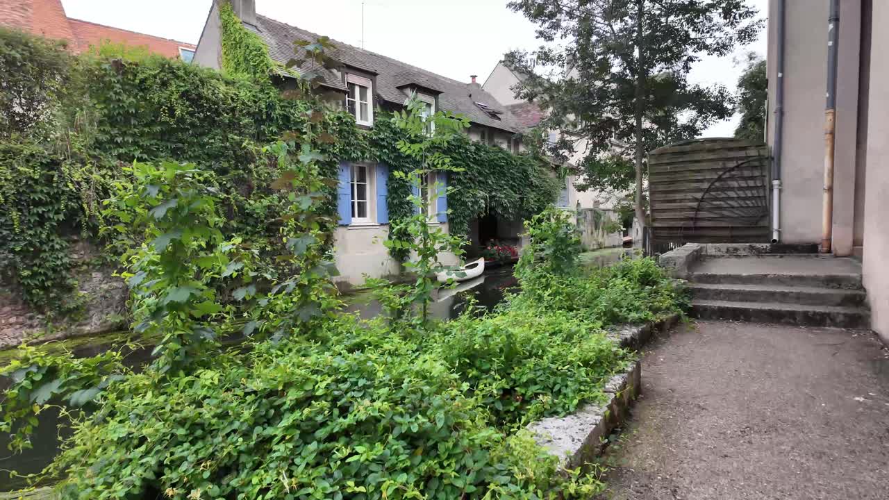 Passage, walkway near river Eure with view over charming old town houses and boat, Chartres, France.
