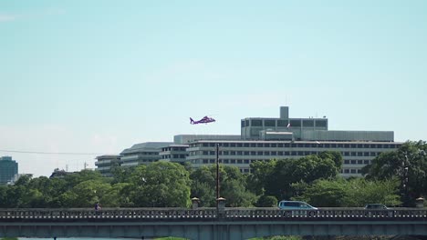 a red rescue helicopter hover above the building at downtown near kamogawa river bridge in kyoto, japan