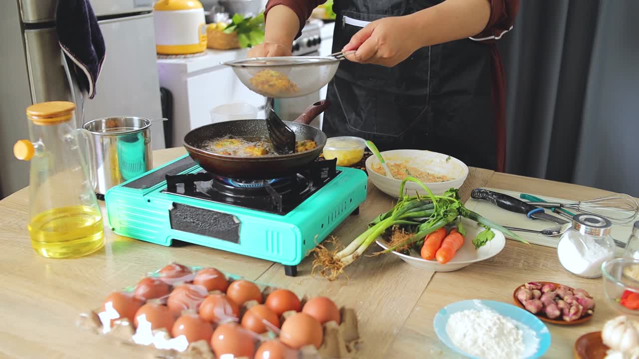 Close-up Bakwan Sayur cokelat keemasan yang sedang ditiriskan dari minyak di meja dapur