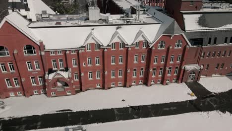 hombre caminando frente al edificio de la universidad del obispo mcgreer hall durante el invierno en lennoxville, sherbrooke, quebec