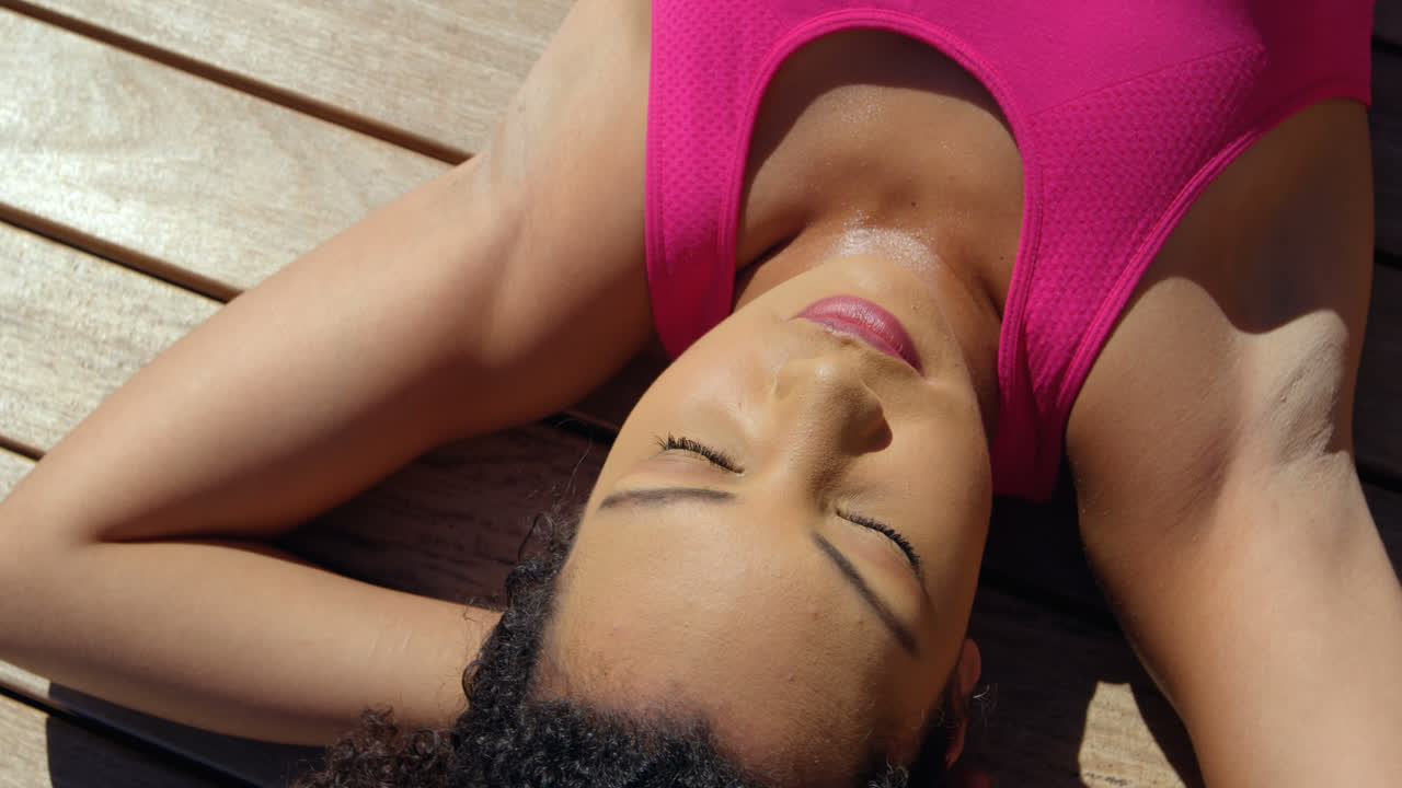 Vista frontal de jovem e bonita mulher mestiça a relaxar num dia ensolarado no quintal de casa 4k
