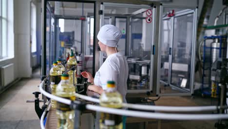interior of automated factory of refined oil production. female worker in uniform controls the work of modern equipment. sunflower oil plant.