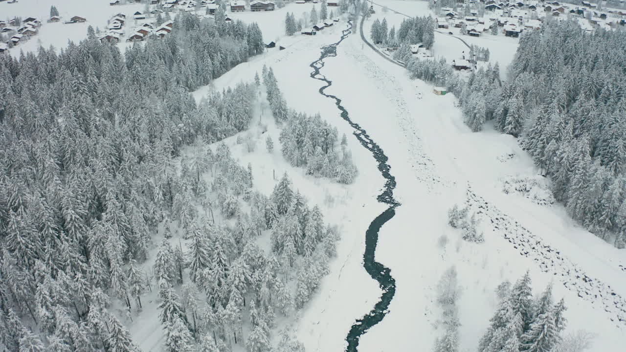 drone siguiendo el río y revelando una hermosa ciudad suiza en un paisaje cubierto de nieve