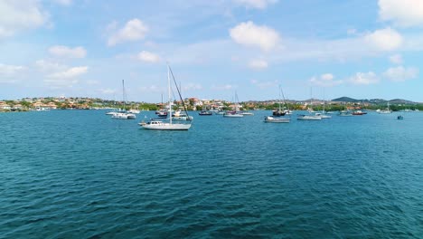 dolly aéreo de bajo vuelo sobre las aguas azules del caribe a veleros anclados en aguas españolas curacao