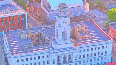 aerial fly national english flag waving over town hall, clock tower building, station in south yorkshire, near barnsley town centre - civic gardens area