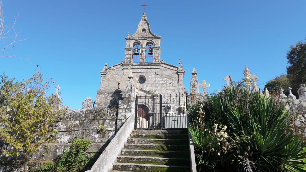 Vista frontale della chiesa di San Salvador de Sabucedo a Porqueira, Ourense, con la sua storica facciata in pietra, campanile, scalinata e architettura religiosa tradizionale sotto un cielo azzurro brillante