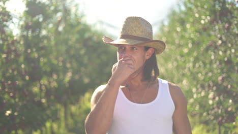 man eating an apple in a sunny orchard