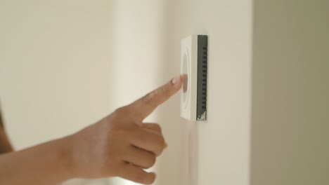 person touching a light switch on a white wall