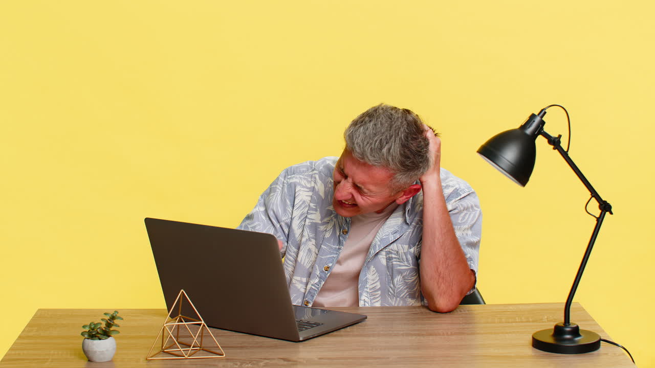 Adult man holding head in frustration while looking at laptop after mistake computer virus problem