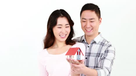 happy couple holding a little house on their hands