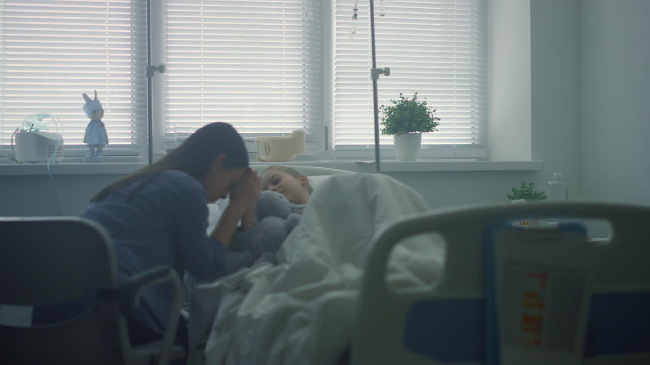 la madre se preocupa por el niño enfermo después de la terapia en la clínica. el niño gravemente enfermo está en la cama.