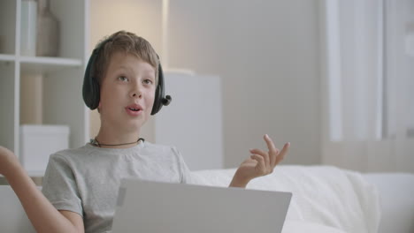 online communication from home of child boy with classmates or parents by laptop with video chat headphones on head