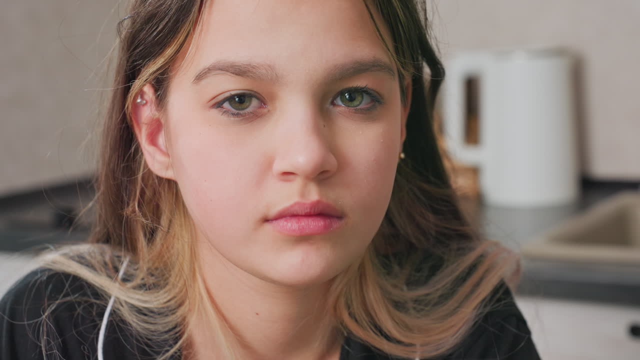 close up of young girl chewing and swallowing food in kitchen setting, utensils visible in background, natural light, candid moment, casual atmosphere, healthy eating, youth, lifestyle