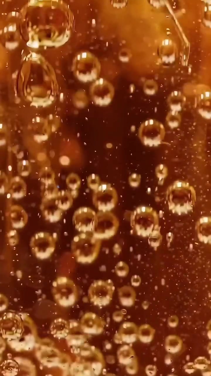 Bolle dorate ipnotizzanti che salgono in un liquido effervescente