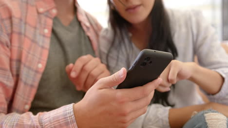 A-diverse-couple-is-using-a-smartphone-at-home-on-the-couch