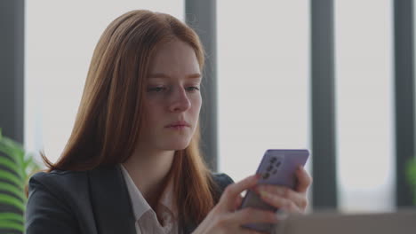 young businesswoman is reading news in mobile phone portrait of serious and depressed lady in office